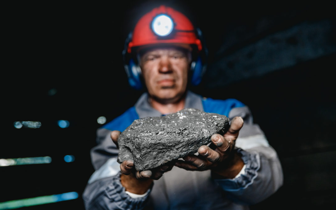 Coal miner holding up a block of coal.